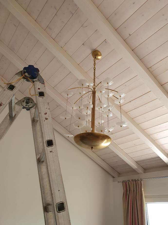Installation d'un lustre haut de gamme suspendu sous plafond mansardé en bois