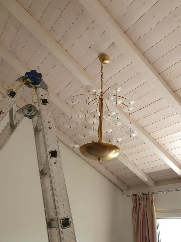Installation d'un lustre haut de gamme suspendu sous plafond mansardé en bois